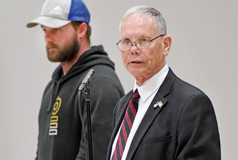 Former Hampton teacher Marlin Seeman leads those attending the Hampton Veterans Day Program through a ceremony for the proper disposal of a faded American Flag. Looking on is Aurora native Austin Allen.