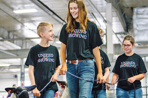 Josh Layman, showman, (left), leads his lamb as a member of the Unified Showing 4-H Club, accompanied by buddy Tatum Terwilliger. Josh, one of the first members of the club, has honed his skills over the years and this summer was the lightweight champion in the sheep show at the Lancaster County Fair. 