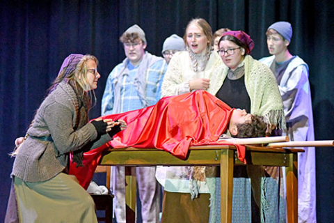 Cast members react during an emotional scene while Bartley, a lead character in “Riders to the Sea” played by Sam Elge, lies dead on the table.