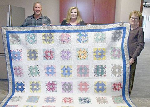 From left, Chad and Dani Klute along with Dani’s mother, Glenna Markham, proudly hold the finished quilt originally started by Chad’s great grandmother, Judie.