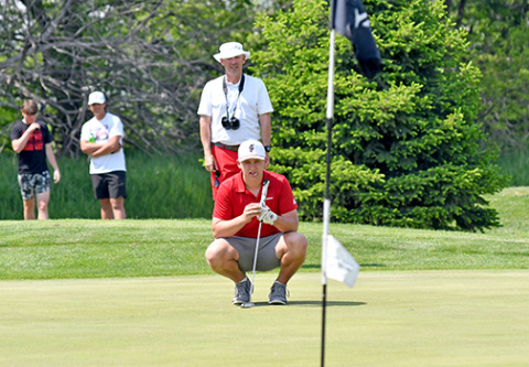Luke Grosshans, shown here reading a putt with some assistance from coach Craig Badura at districts, finished tied for 28th at the Class B state golf meet. 