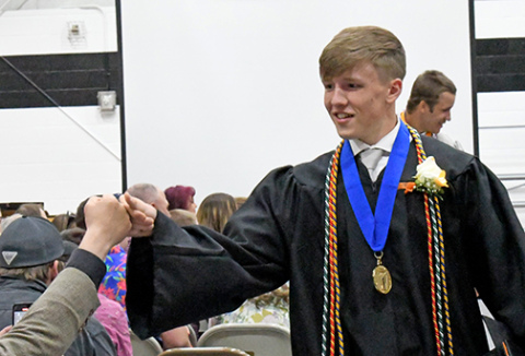 Giltner graduate Phillip Kruetz fist bumps family and friends as he and his high school classmates complete their 2024 graduation ceremony. 