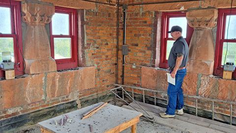 In the uppermost floor of the Hamilton County Courthouse tower custodian John Bish holds his hand over the photoelectric switch to light up the beacons mounted in each middle window. 