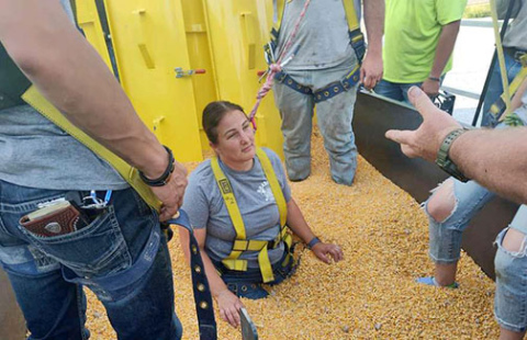 EMT captain Erin Ditloff goes waist deep in the training trailer to help firefighters train for a grain rescue scenario. Coffer dams were used to prevent grain from falling back as firefighters dig Ditloff and a training dummy out throughout the evening.