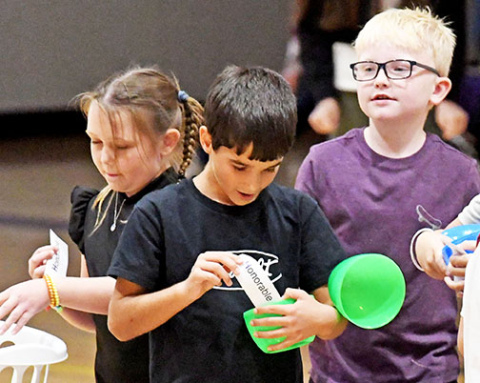 Josh Weedin opens his HAWK egg on the first day of school at Hampton to learn he is a member of the Honorable Family along with other elementary and high school students as well. At left is Melori Bennett and at right is Cole Haberer.