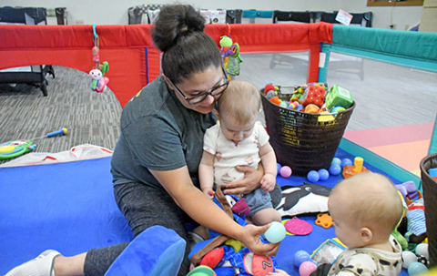 Infant teacher aid Alisha Lawson holds and plays with Haisley Scheierman-Hradecky in the Hampton Daycare Center’s “Hawk’s Nest,” the room for children between 6 weeks and 18 months of age.
