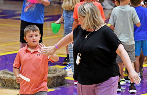Hampton Elementary Principal Angie Arndt reaches back to give 2nd grader Chance Goertzen a high five after he opens his egg revealing he is a member of the Honorable Family. 
