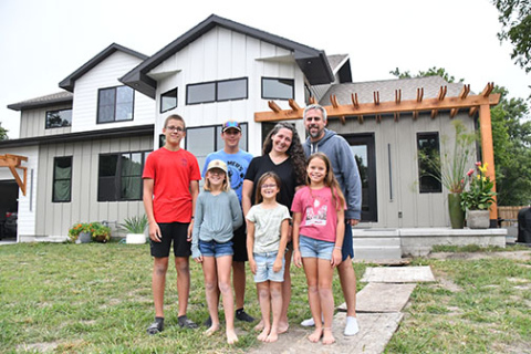 Joseph and Kylee Ochsner stand outside their new five-bedroom home on L Street with their children Gideon, Eden, Boaz, Zipporah and Leah. Pictured below is the fire scene at their home on July 14, 2023.