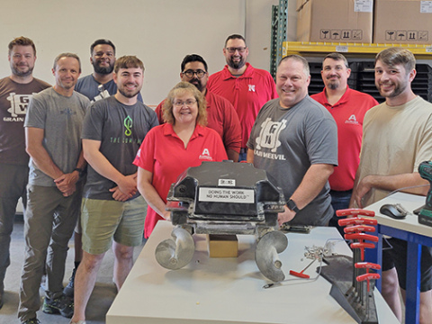 Employees from both the Grain Weevil and Aurora Boardworks display one of the early production models of the visionary robot, parts of which were produced here in Aurora.