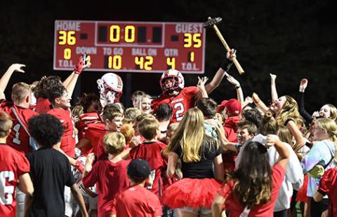 Aurora senior QB Booker Scheierman holds the hammer trophy high as the Huskies and AHS students celebrate defeating rival Grand Island Northwest 36-35 in a wild Homecoming comeback victory Friday. Aurora trailed 28-0 in the first half before scoring the game-winning two-point conversion with 15 seconds left. 