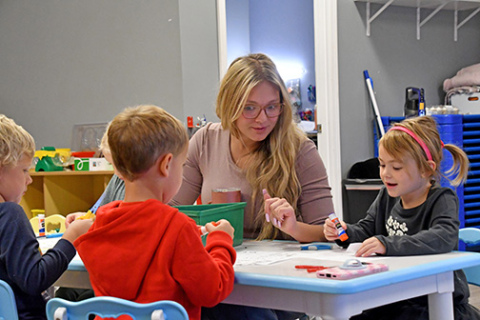 The Little Stingers Child Care Facility is set in motion to build a foundation on the empty lot south of Giltner Elementary School starting the third week of November. Staff member Gracie Oman (center) helps preschool students with their activity sheets during their morning class on Oct. 16. Students include, from left: Cyrus Wilcox, Thayer Barnes and Della Mae Lott.
