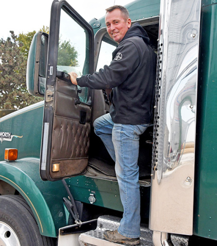 Nate Goertzen climbs into one of the semis he is using to haul white corn to the grain bin from the nearby field he’s harvesting with the help of his father, Dennis.