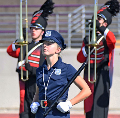 Drum major Savanna James, in costume as a police officer, leads the Aurora Marching Huskies onto the field during Saturday’s field show.