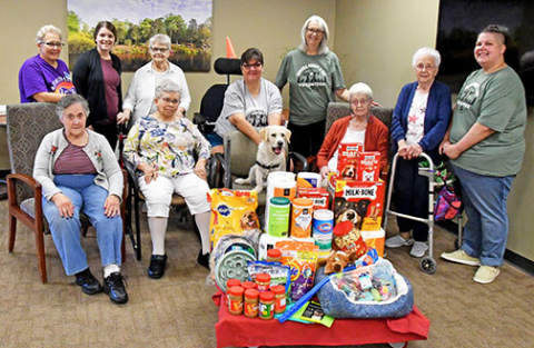 Comfort dog, Finn, sits in the middle of a group of his special friends and shows off the supplies that were donated for Aurora Adopt a Pet in honor of his first birthday at Memorial Community Care. In the front row, from left, are Mary Crawford, Geri Hartzell, Finn, Jane Larsen, Noni Troester and MCC activities director and Finn’s handler, Jessie Morales; back row, Laurie Wessels, Katelyn Honas, Carol Hauf, Rhonda Cloet and Dawn Haymart.
