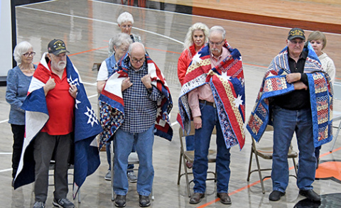 Four Giltner veterans were honored with Quilts of Valor during Giltner Public Schools’ Veterans Day program. The quilts were presented by the Nimble Thimble Quilt Guild, the Grand Island Quilt of Valor group. Veterans who received their quilt of valor includes, front from left: Allen Miller, Brian Miller, Kevin Miller, Kenneth Paul Colburn. The veterans were drapped with their quilts by Allen’s wife Kay, Janie Murphy, Darci Higgins Williamson and Kenneth’s wife Ann respectively during the ceremony. 