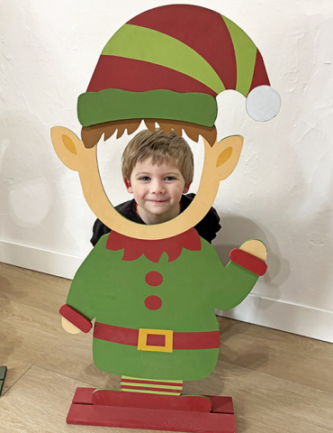 Young Stetson Avina creates a photo op for mom Heather, posing as an elf shortly after sitting on Santa’s lap during the Come Home to Christmas celebration Nov. 30 in Aurora.
