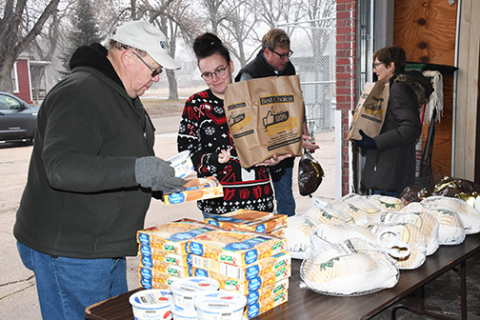 Food pantry volunteers help distribute bags packed with ham or turkey and all the trimmings for a special meal during Saturday’s annual holiday food distribution event.