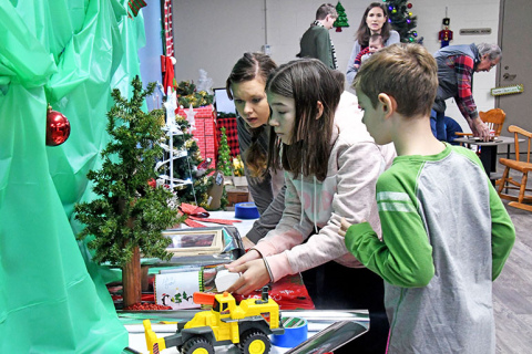Lily Francl (center) presses a button that unlocks a tool for the escape room’s next puzzle. With her is aunt Kim Bossert and Lily’s brother Nolan.
