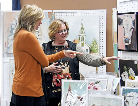 Artist Tonya Grosshans (left) talks about her realistic and abstract paintings with Art Walk patron Beverly Goertzen during the September event in downtown Aurora.