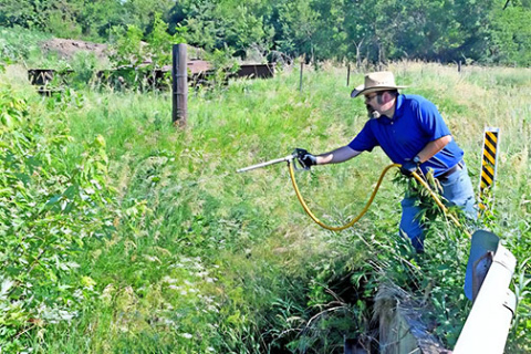 Hamilton County Noxious Weed and Highway Supt. Jeremy Brandt sprays weeds in a road ditch near a county bridge. He is responsible for knocking out noxious weeds and invasive species along the county’s 1,000 miles of roads and enforcing weed control on private lands. 