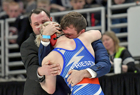 HPC wrestler Gage Friesen gets a celebratory embrace from coach Martin Phillips after winning the 150-pound Class D weight class at the state tournament.
