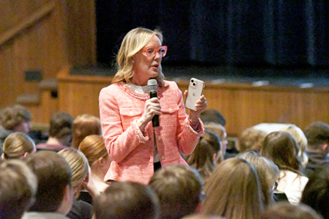 Aurora High School Health and Wellness Day speaker Suzie Fogarty holds up her iPhone to make a point during her keynote address to high school students last Wednesday. Fogarty reported that today’s high school students spend an average of 7-1/2 hours a day looking at screens, and that’s on top of the time computers are used for study. 