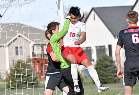 Aurora’s backup keeper Calvin Miller catches both the soccer ball and Crete’s Alfredo Herrera in the air at the net during the Huskies’ 5-2 loss to the Cardinals Thursday. 