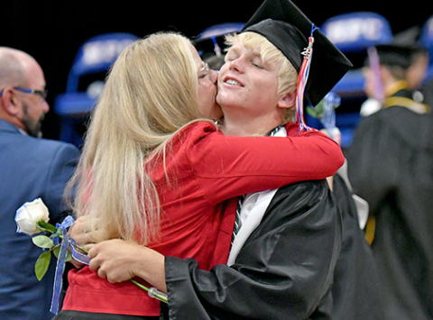 High Plains co-salutatorian Gage Friesen presents his Mom, Talia Peterson, with a flower while she sneaks in a kiss on his cheek during graduation ceremonies Saturday in Polk. 