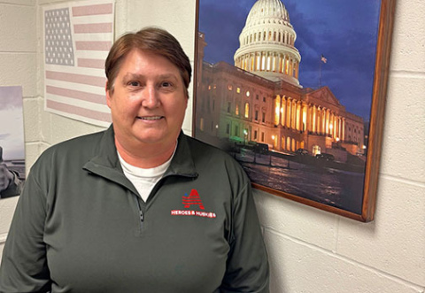 American history teacher Brenda Klawonn stands in front of a photo from Washington D.C., a city she visited 15 times as part of student projects like Heroes & Huskies.