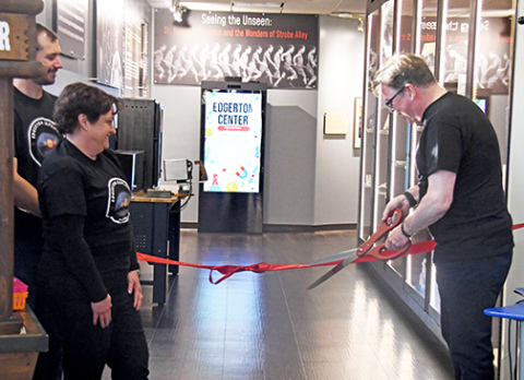 Edgerton board president John Nelson cuts the ribbon on the Explorit Center's remodeled Strobe Alley exhibit. Also present from left are board member Brett Mitchell and John’s wife, Deb, who along with her husband represented the Nelson family who helped fund Strobe Alley Reimagined.