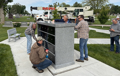 Members of the installation crew polish the new columbine unit after hoisting it into place at the Aurora Cemetery June 4.