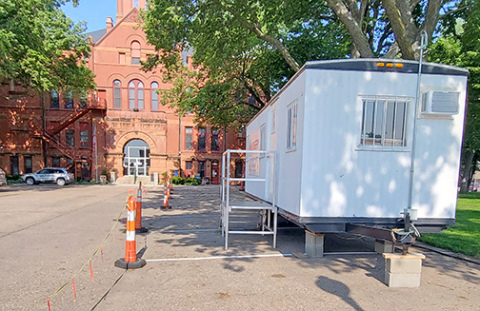 Traffic cones and a construction trailer mark the north side of the courthouse parking lot which will be used to store equipment and materials during the exterior renovation of the building starting on June 16. The courthouse steps will be replaced first but the ground floor entrance will remain open throughout the project. The restrooms will also be accessible during A’ROR’N Days at the end of the month. 