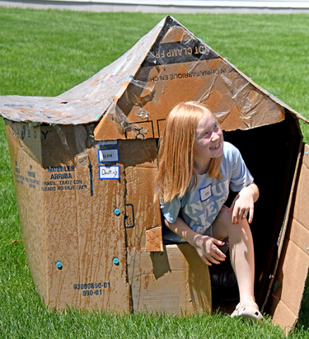 Cardboard Creations camper Nora Tompkins rises from her cardboard house after it withstood assaults of water, ice and wind.