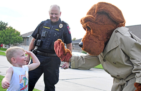 Daxyn Rust reaches for a high five with McGruff during a visit to Lincoln Creek’s pocket park.  