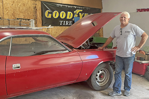 Bill Gowen stands next his red 1970 Dodge Challenger in his garage in Aurora. He originally bought and modified the car in high school and is excited to restore it in coming days.