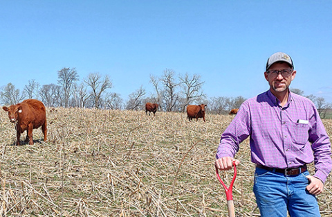 Brian Brhel stands on one of his no-till fields with grazing cattle, showcasing integrated crops and livestock practices that support soil health and farm resilience. (Photo credit Caro Córdova UNL Department of Agronomy and Horticulture)