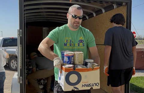 Rotarian Justin Wolf helps unload boxes of paint cans at the Clean Community Systems facility in Grand Island. Pictured behind him is Jacob Arendt.