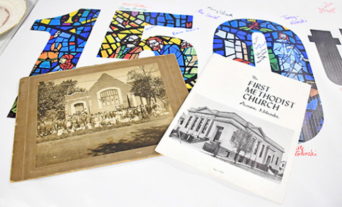 Several tables in the fellowship hall of the Aurora United Methodist Church display photos and other historical artifacts from the church’s 150-year history. At left above are photos of the original church buildings of the Evangelical United Brethren and First Methodist churches that united in the 1970s to form the current United Methodist congregation. 