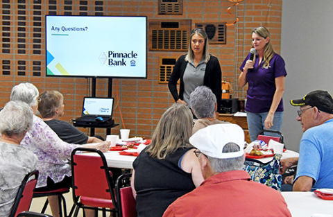 Selena Longoria (left) and Faith Gustafson of the Aurora Branch of Pinnacle Bank give a presentation on how to avoid being the victim of a scam to an audience at the Aurora Senior Center on Friday. 