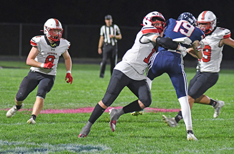 Junior Hudson Decker puts a hit on the Patriots’ Nick Mousel during Friday’s game at Adams Central.