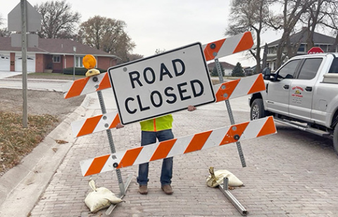 A crew member from Mid-Nebraska Land Developers removes the final “Street Closed” barricade on 1st Street.