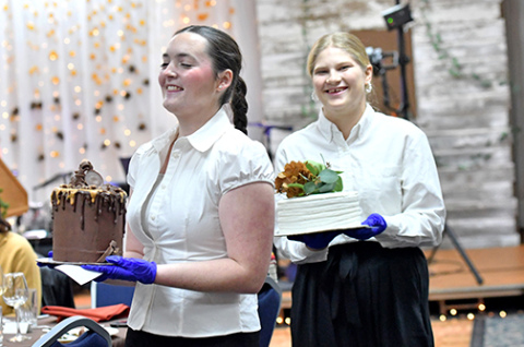 Adelynne Hendrickson and Violet Carstensen walk around tables showcasing the cakes in the Harvest Gala’s dessert auction Saturday night.
