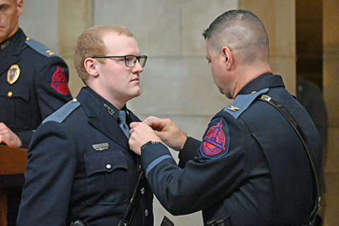 Newly sworn-in NSP trooper Dan Christenson receives his badge during a ceremony at the state capitol on Friday. 