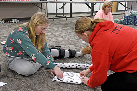 Aurora seniors Savanna James and Micole Yockey work on the finishing touches on one of the gifts that they wrapped Thursday during YEP’s gift-wrapping event.