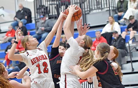 Aurora’s Maddie Ramaekers (12) and Paisley Bartek (15) are among a cluster battling for a rebound during Monday’s 68-41 win over Omaha Roncalli. 
