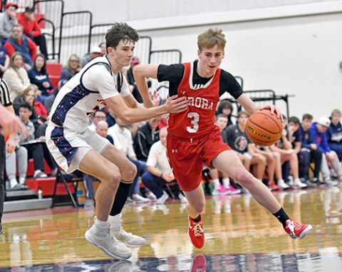 Aurora’s Brooks Handrup looks for a lane in the second half of the Huskies’ 44-36 win over Adams Central Saturday, claiming a second straight Central Conference tournament championship. 