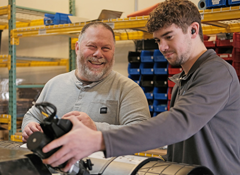 Chad Johnson (left) laughs while chatting with mechanical engineer Cole Oswald while adding parts to a robot. (Photo by Lev Gringauz/Silicon Prairie News)