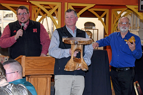 Auctioneer Jamie Bergmark, left, calls for bids during Monday’s live auction at the Plainsman, while volunteers Greg Bonifas and Eric Lohrmeyer assist.