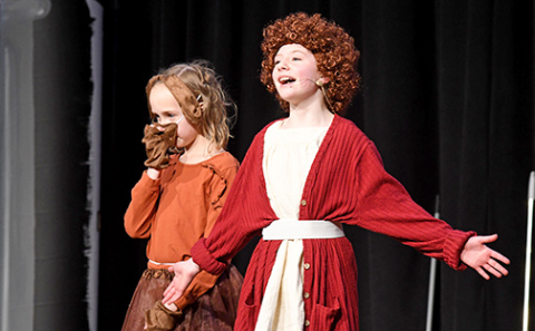 Cassidy Goertzen (right) as Little Orphan Annie sings with her faithful dog Sandy (played by Sophia Clinch) by her side. 