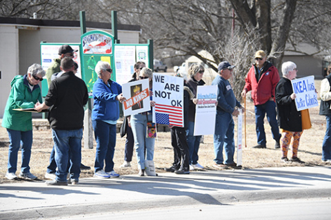 A crowd estimated at 60-70 people held up signs along Highway 14 Saturday as part of a nationwide No Kings rally, protesting actions and policies of the Trump administration.